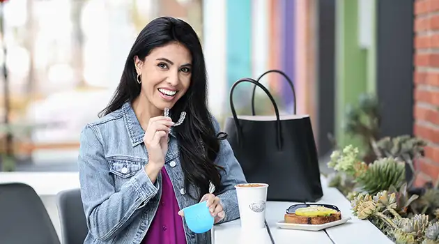 woman smiling as she is putting her Invisalign braces away while she eats