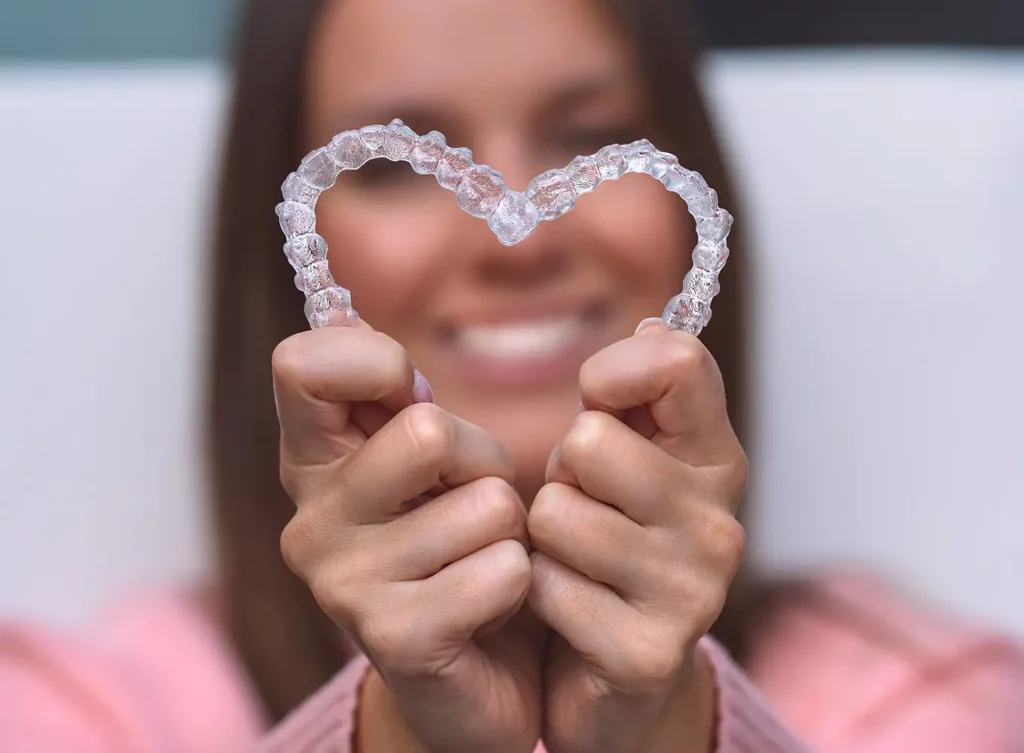 woman holder her Invisalign clear aligners in a heart shape